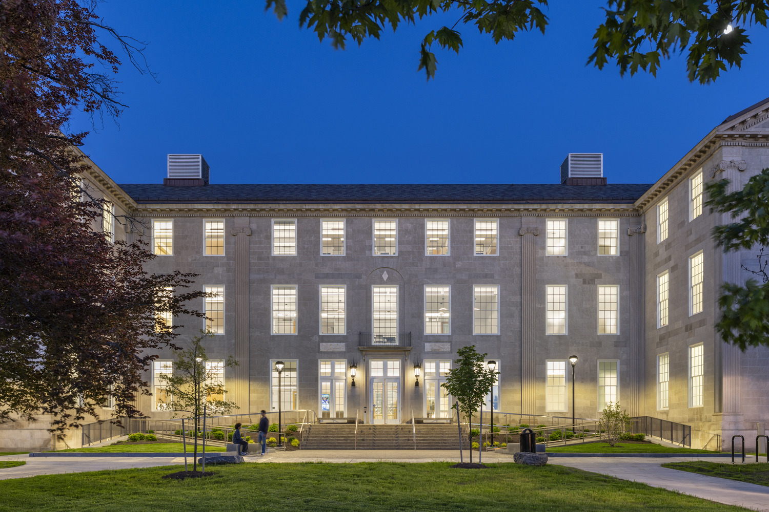 West entrance of Foster Hall at dusk with lights on.